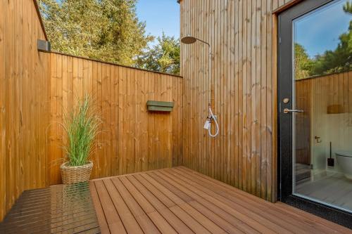 a wooden deck with a shower and a plant on it at Feriehus 1161 in Ringkøbing