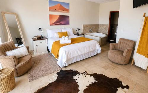 a bedroom with a bed and two chairs and a sink at Sunset View 10 @ Langstrand in Langstrand