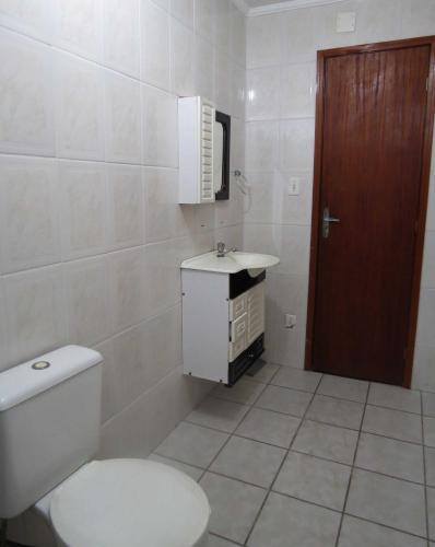 a white bathroom with a toilet and a sink at Hotel Caiçara in Praia Grande