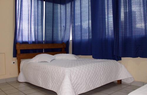 a bedroom with a bed with blue curtains at Hotel Caiçara in Praia Grande