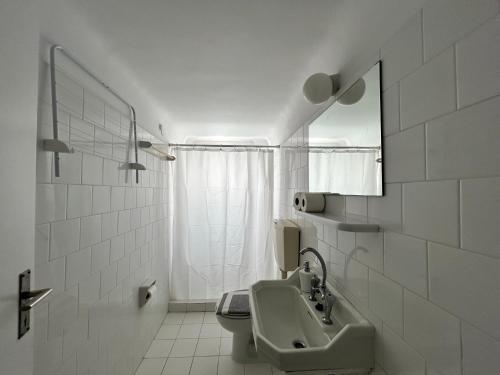a white bathroom with a sink and a mirror at Tinion Hotel in Tinos