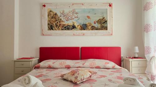 a bed with a red headboard and a painting on the wall at Casa Stelle Marine in Palau