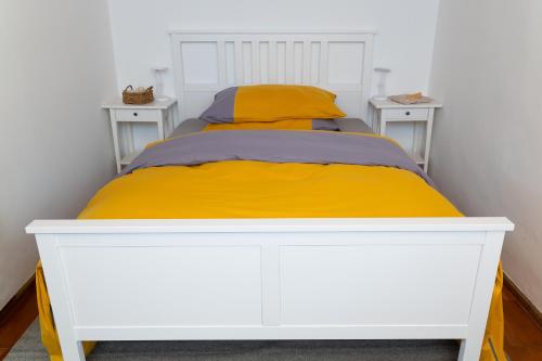 a white bed with yellow sheets and two night stands at Ferienhaus-Weinmeyer in Paasdorf
