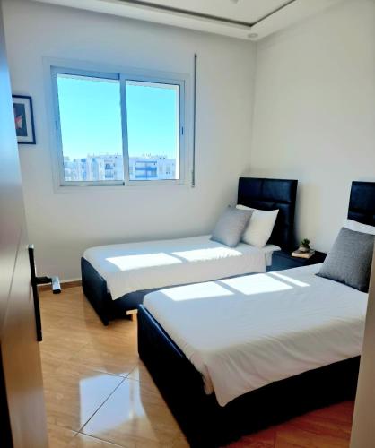 two beds in a room with a window at APPARTEMENT DE LUXE 3 Façades in Ben Slimane