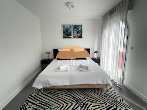 a bedroom with a bed and a large window at Le Clos Brémontier in Soorts-Hossegor