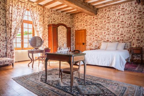 a bedroom with a bed and a table and a desk at Château du Hardas in Segré