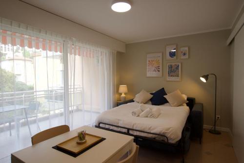 a bedroom with a bed and a table and a window at Monte Carlo Terrace Monaco in Beausoleil