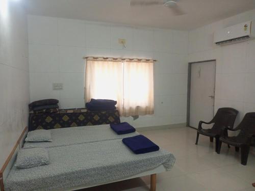 a room with a bed and chairs and a window at Madhav Villa Only Family in Dwarka
