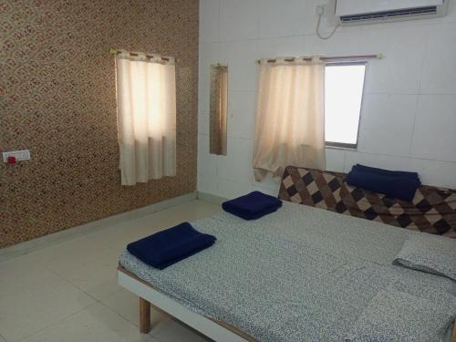 a bedroom with a bed with blue cushions and a window at Madhav Villa Only Family in Dwarka
