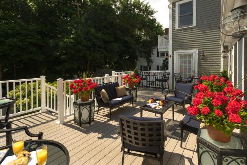 a deck with chairs and tables and flowers on a house at Old Harbor Inn in Chatham