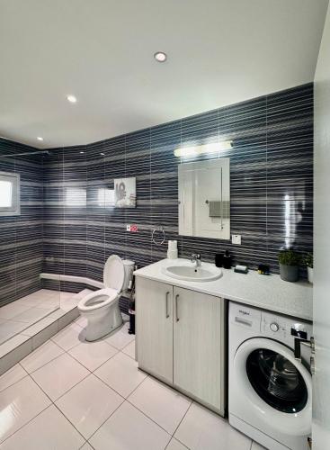 a bathroom with a toilet a sink and a washing machine at GA apartments in Kato Pyrgos