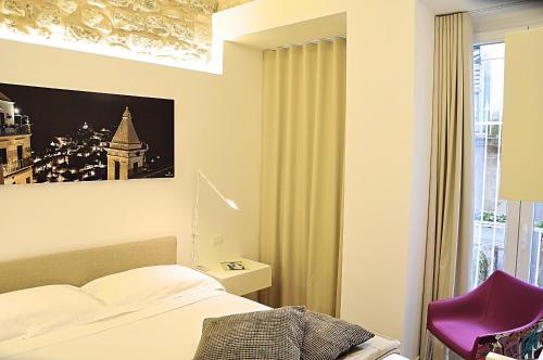 a bedroom with a bed and a purple chair at Keys of Sicily - Appartamenti Modica Bassa in Modica