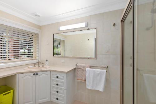 a white bathroom with a sink and a shower at Family stay minute walk from Hargraves beach in Norah