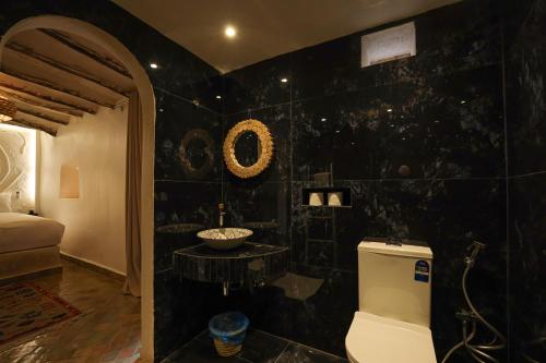 a black tiled bathroom with a toilet and a sink at Bohemian lodge guest house in Aït Namous