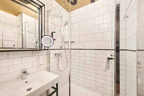 a bathroom with a shower and a sink and a mirror at voco Budapest D8 by IHG in Budapest