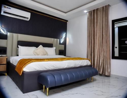 a bedroom with a large bed with a blue bench at Orchid - Bliss Hotels in Lagos