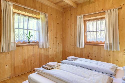 two beds in a wooden room with two windows at Ferienhaus Schwarzenbach in San Genesio Atesino