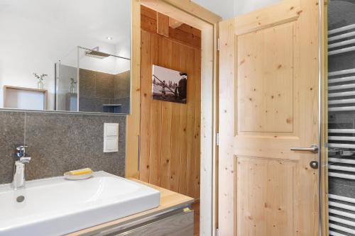 a bathroom with a white sink and a wooden door at Ferienhaus Schwarzenbach in San Genesio Atesino