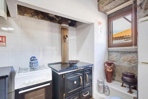 a kitchen with an old stove and a window at Casa da Adega in Sá