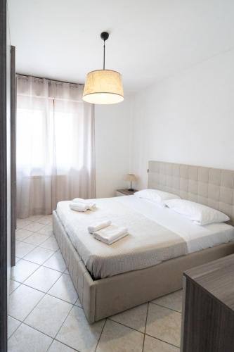 a white bedroom with a large bed with towels on it at A Due Passi dal Mare in Chioggia