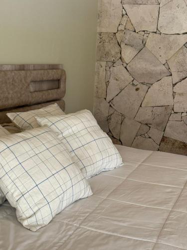 a bed with two pillows and a stone wall at Rio los Patos in Barreal