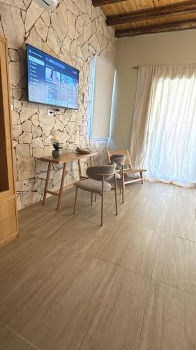 a living room with a table and a tv on a stone wall at Rio los Patos in Barreal