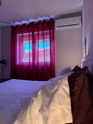 a bedroom with a bed and a window with red curtains at Downtown Deluxe Apartment in Shkodër