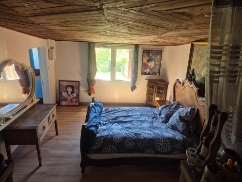 a bedroom with a blue bed and a mirror at Chalet de la vallée in Souppes-sur-Loing