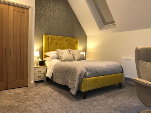 a bedroom with a bed with a yellow headboard at Christmas Hill Farm in Gaydon