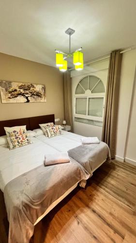 a bedroom with a large white bed with a window at Apartamento La Celestina in La Puebla de Montalbán