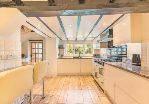 a kitchen with white cabinets and a blue ceiling at Beautiful Thatched Cottage with Outdoor Pool, Secure Garden, Dog & Family Friendly! Chichester Holiday Properties in Bosham