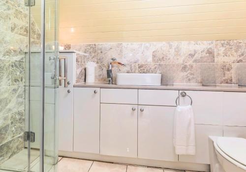 a bathroom with white cabinets and a glass shower at Beautiful Thatched Cottage with Outdoor Pool, Secure Garden, Dog & Family Friendly! Chichester Holiday Properties in Bosham