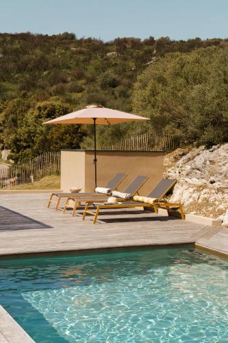 a group of chairs and an umbrella next to a pool at Villa Nebbiu Vista in Oletta