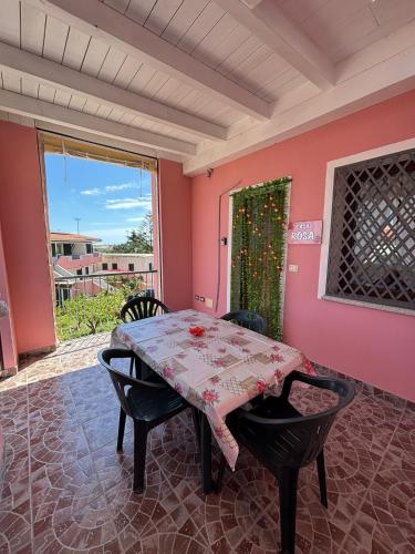 a table and chairs in a room with a pink wall at Appartamento Rosa in Orosei