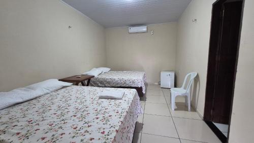 a room with two beds and a table and a chair at Chalé Renilton Turismo in Santo Amaro