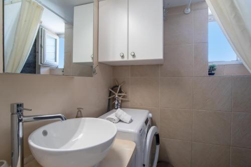 a bathroom with a sink and a washing machine at Anna's Apartment Marmara Paros in Kampos Paros