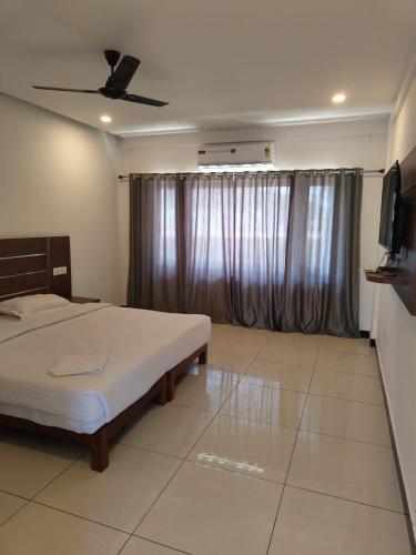 a bedroom with a bed and a flat screen tv at Hotel Trees Thekkady in Thekkady