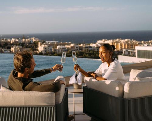 a man and a woman sitting at a table with wine glasses at voco Malta by IHG in St. Julianʼs