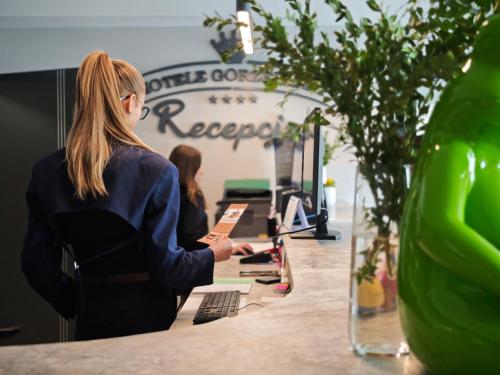 a woman sitting at a counter with a computer at Hotel i Apartamenty Gorzelanny Dźwirzyno in Dźwirzyno