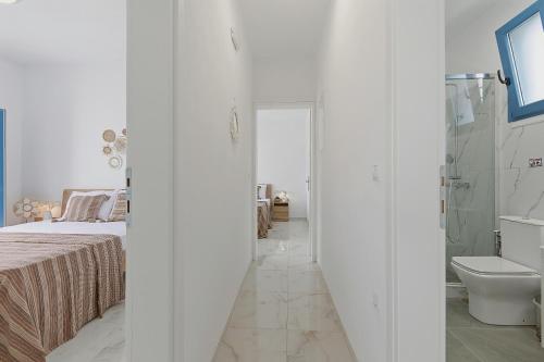 a white room with a bed and a bathroom at Cassiopeia in Akrotiri