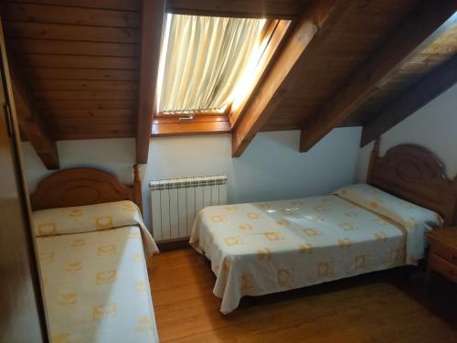 a bedroom with two beds and a window and wooden ceilings at Barruera duplex 2 bedrooms heating in Barruera