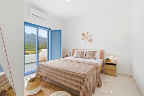 a white bedroom with a bed and a balcony at Cassiopeia in Akrotiri