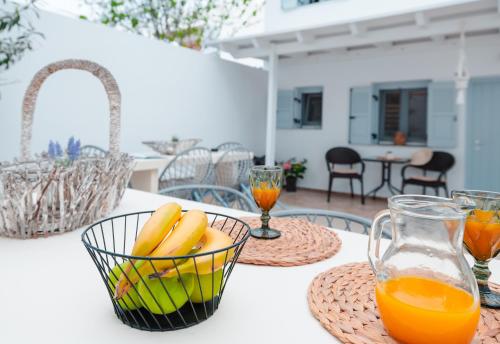 a table with a bowl of fruit and two glasses of orange juice at Begi Luxury Villas in Karterados
