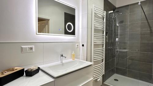 a white bathroom with a sink and a shower at Ferienwohnungen EULE in Lutherstadt Wittenberg