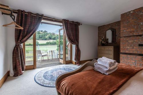 a bedroom with a bed and a balcony with a view at Stud Farm House in Bleddfa