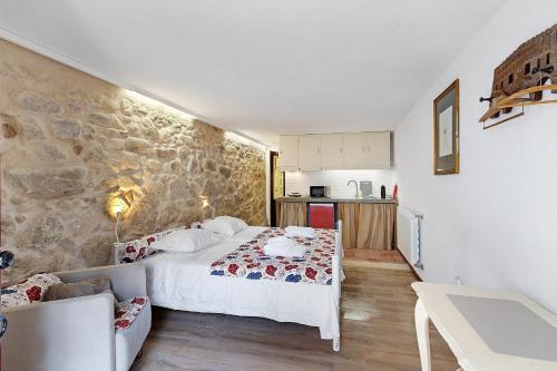 a bedroom with a white bed and a stone wall at Portas de Caminha I in Caminha