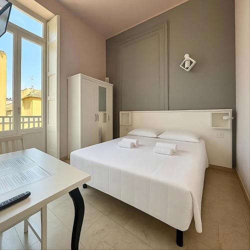 a bedroom with a bed and a desk with a laptop at Margherita Rooms in Catania