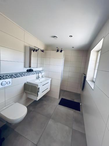 a white bathroom with a toilet and a sink at Ferienwohnung am Vechtedamm in Hoogstede