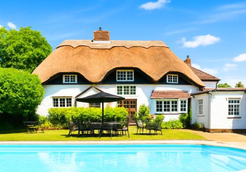 a thatched house with a pool in front of it at Beautiful Thatched Cottage with Outdoor Pool, Secure Garden, Dog & Family Friendly! Chichester Holiday Properties in Bosham