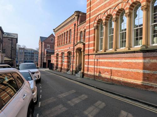 a street with cars parked next to a brick building at The Old Fire Station Luxury Apartment in York